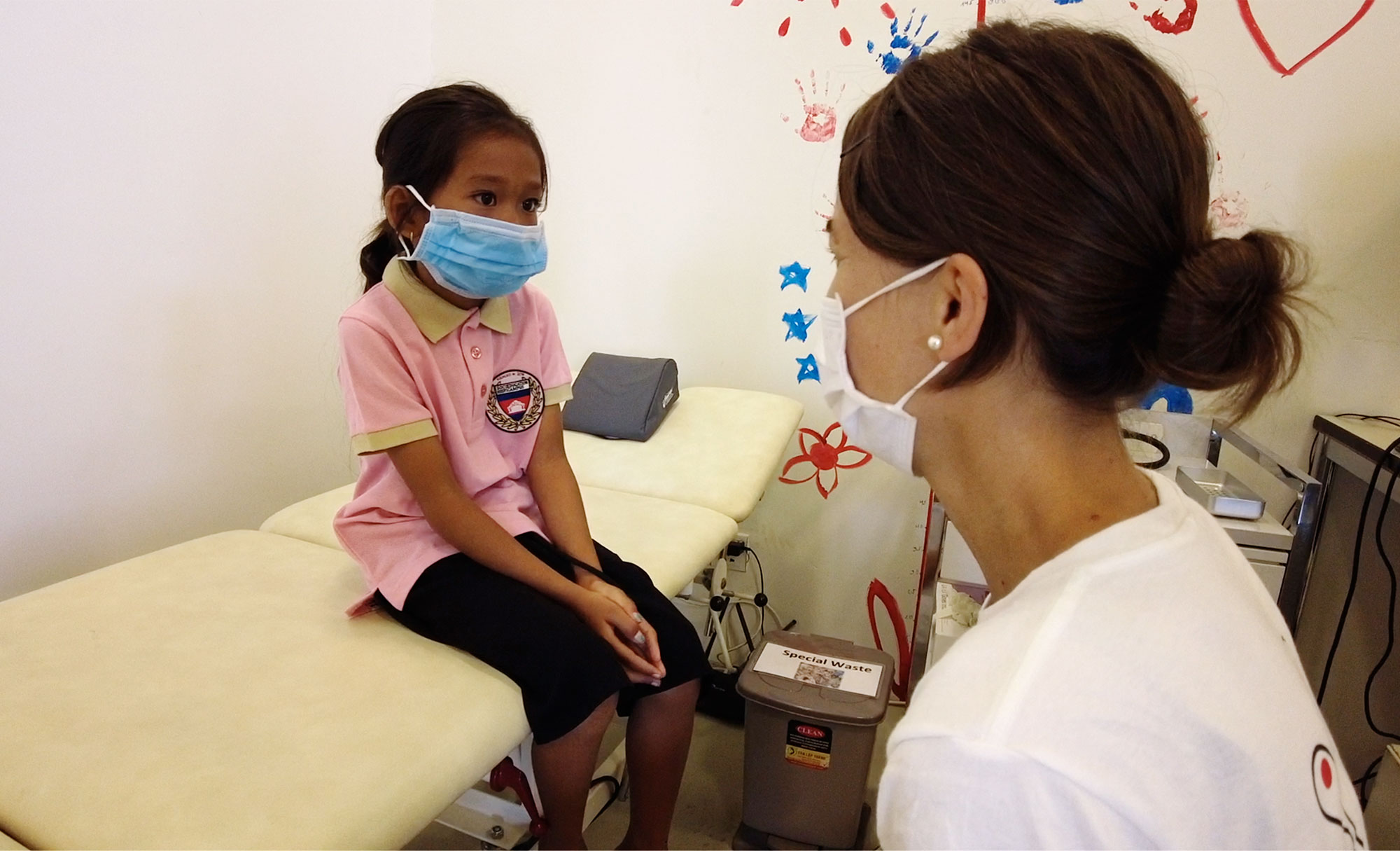 Une médecin parle avec un enfant assis sur une table d’examen.