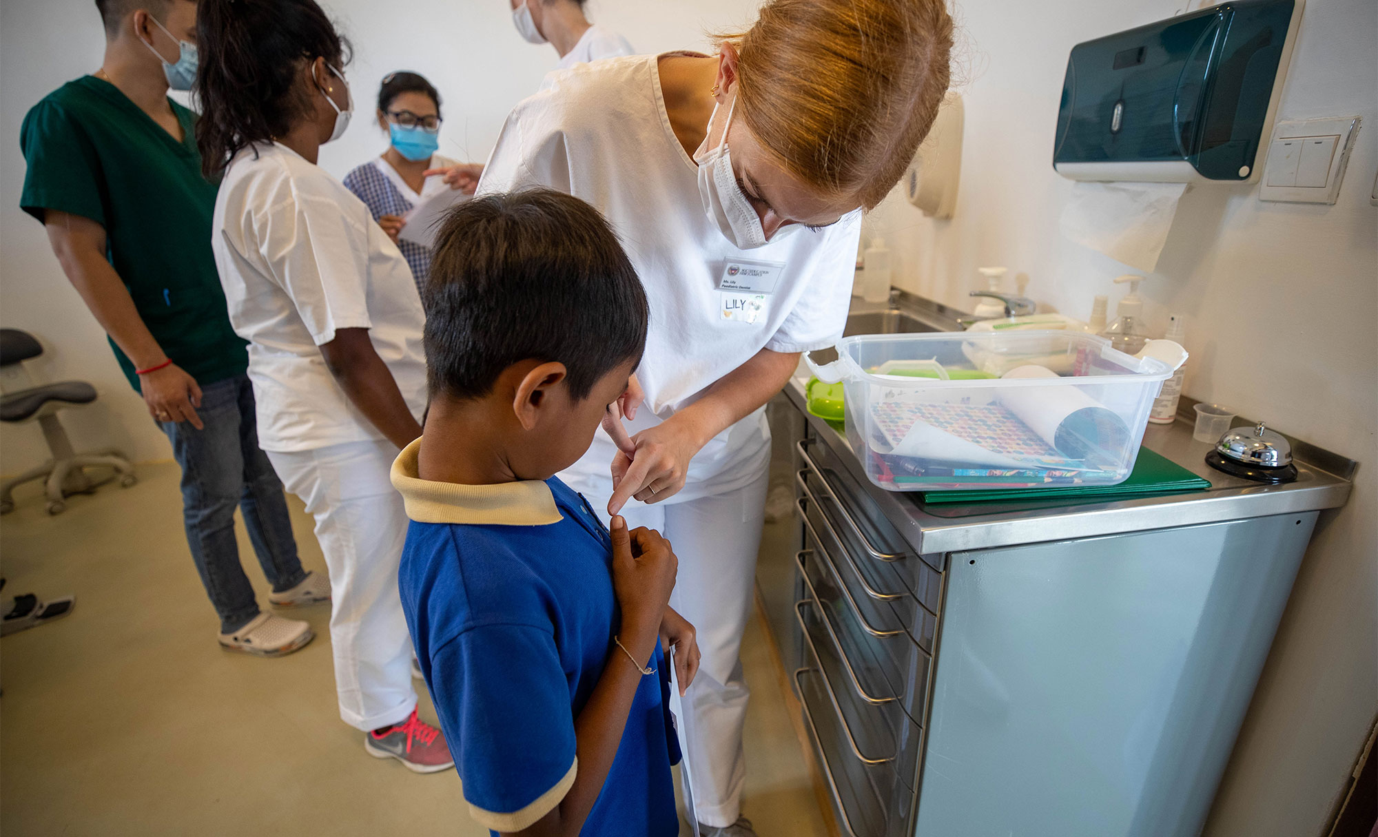Un dentiste accompagne un enfant au lavabo de la clinique.