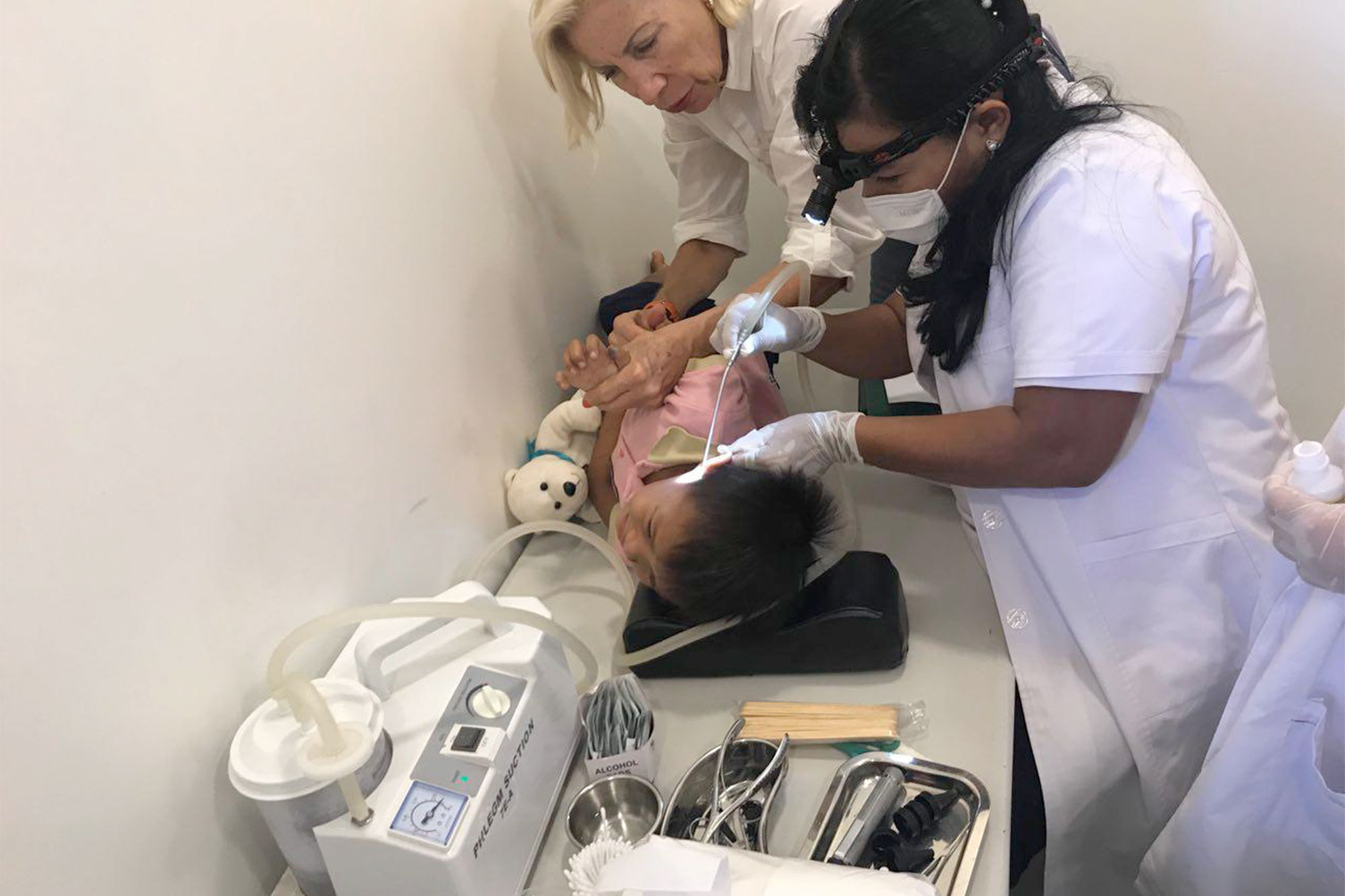 Une équipe dentaire soigne un enfant dans un fauteuil de soins.