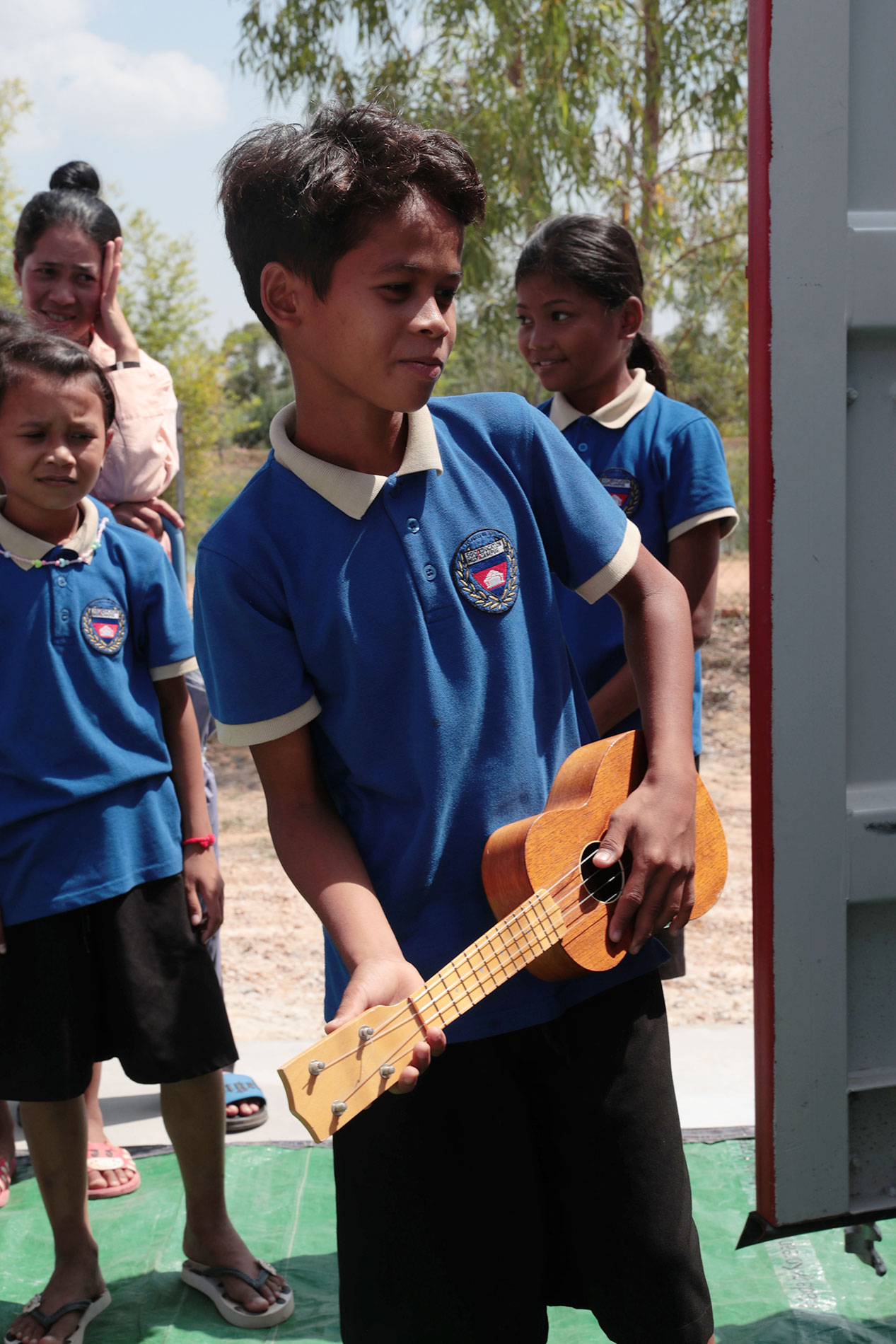 Un enfant tient une guitare lors de la remise des instruments.