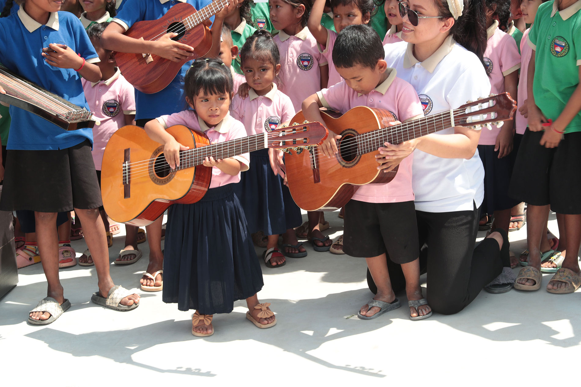 Des enfants tiennent des guitares lors de la remise des instruments de musique.