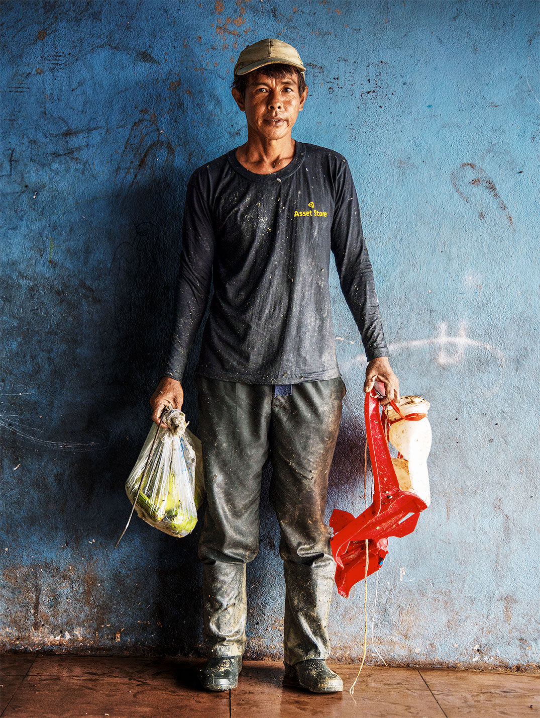 Un homme tenant des sacs se tient devant un mur bleu.