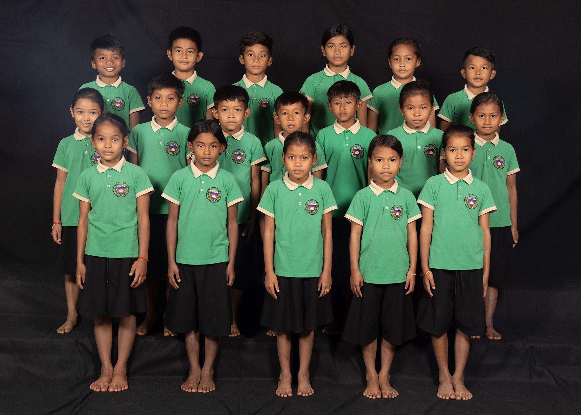 Portrait de groupe d’enfants en uniformes scolaires verts.