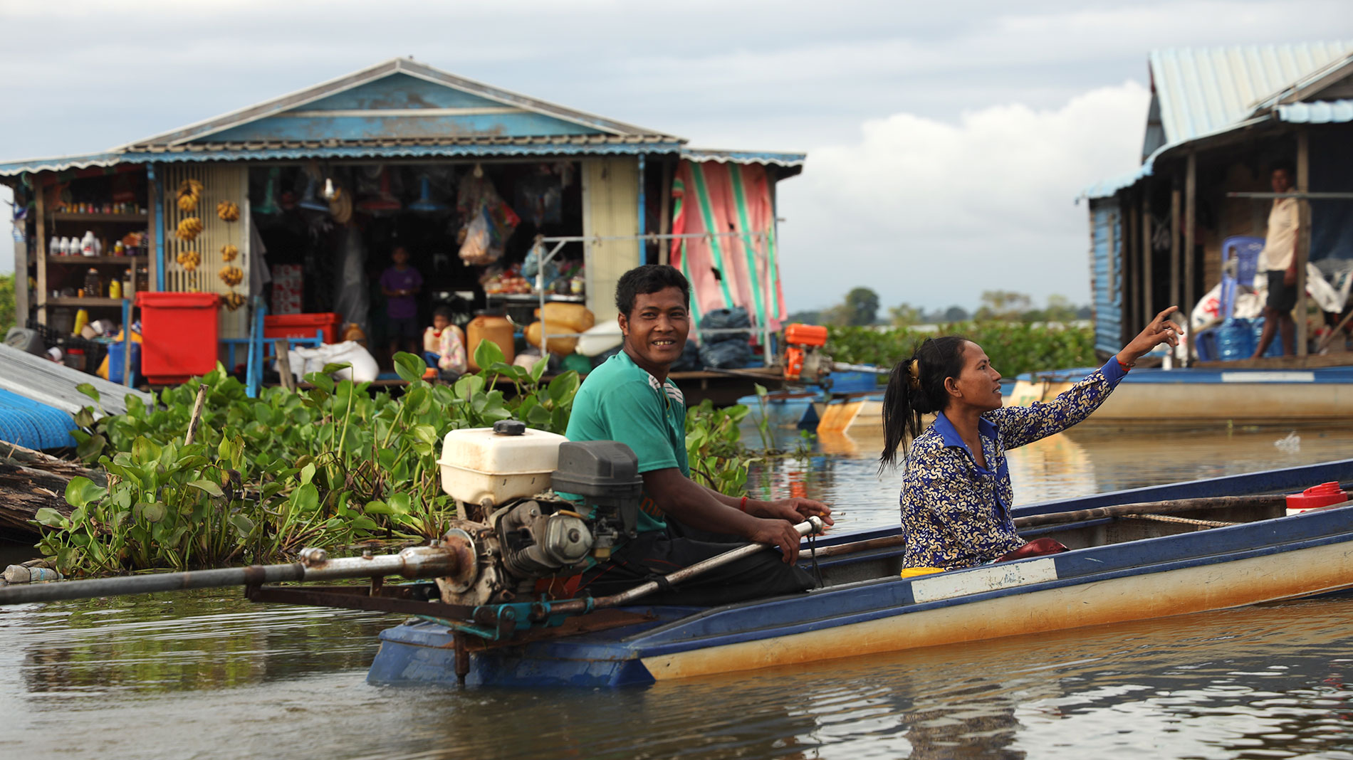 Des personnes en bateau entre des maisons inondées.