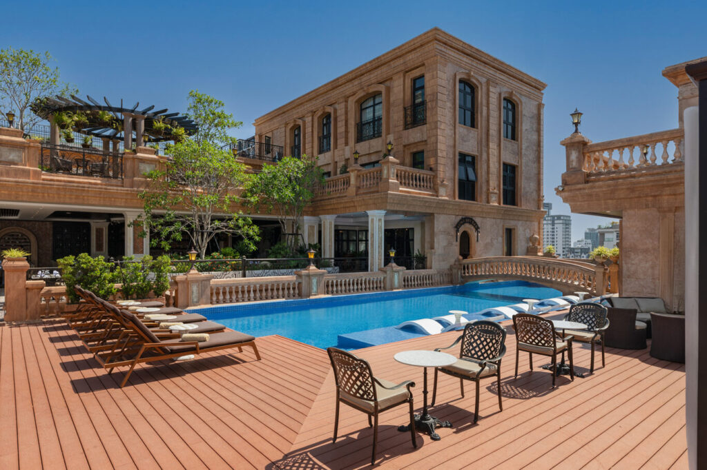 Hotel pool with sun loungers on a wooden deck.