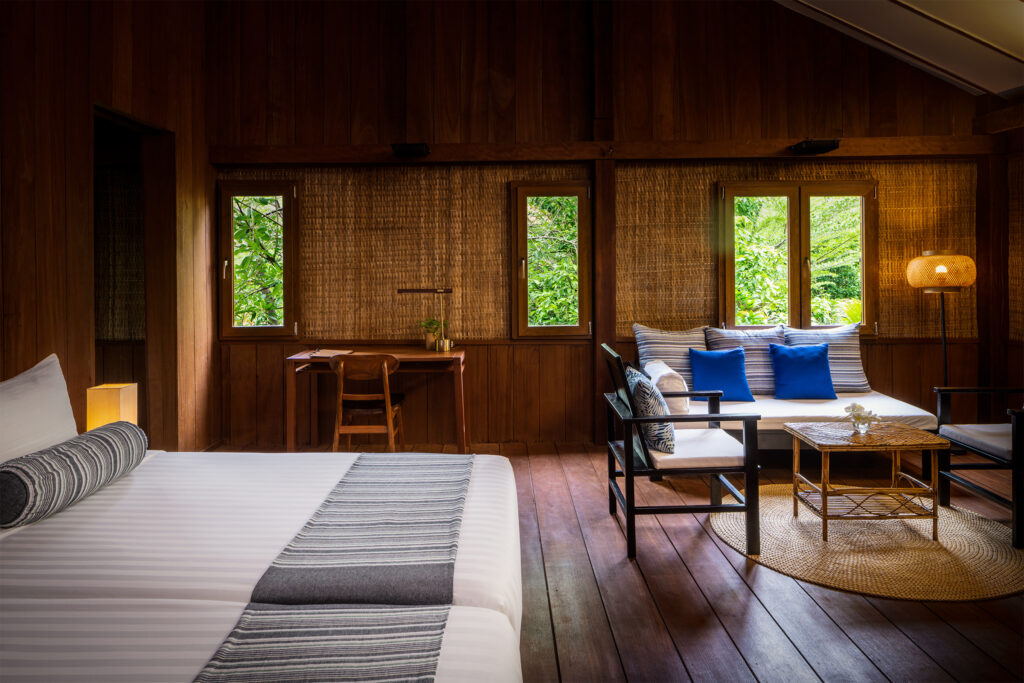 Bedroom and living area in a wooden bungalow at Farmhouse Resort.
