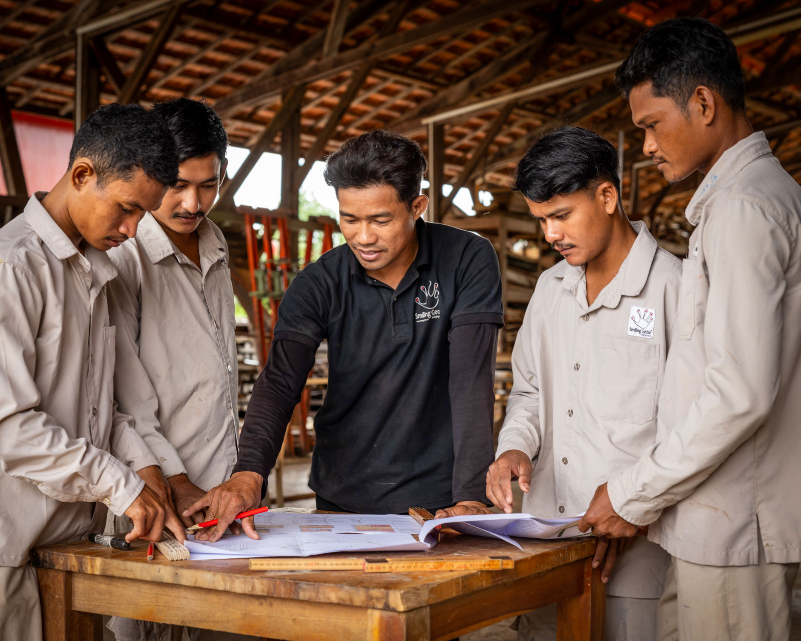 Des apprentis examinent un plan dans l’atelier de menuiserie.