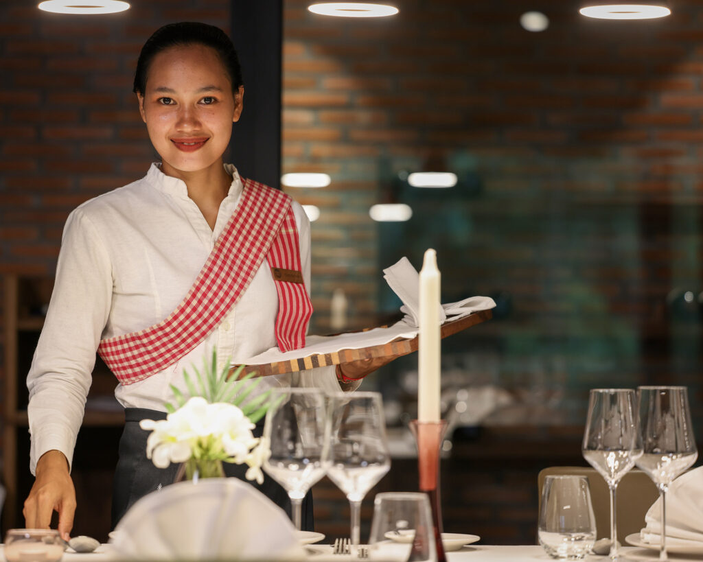 Une employée du service près d’une table dressée au restaurant.