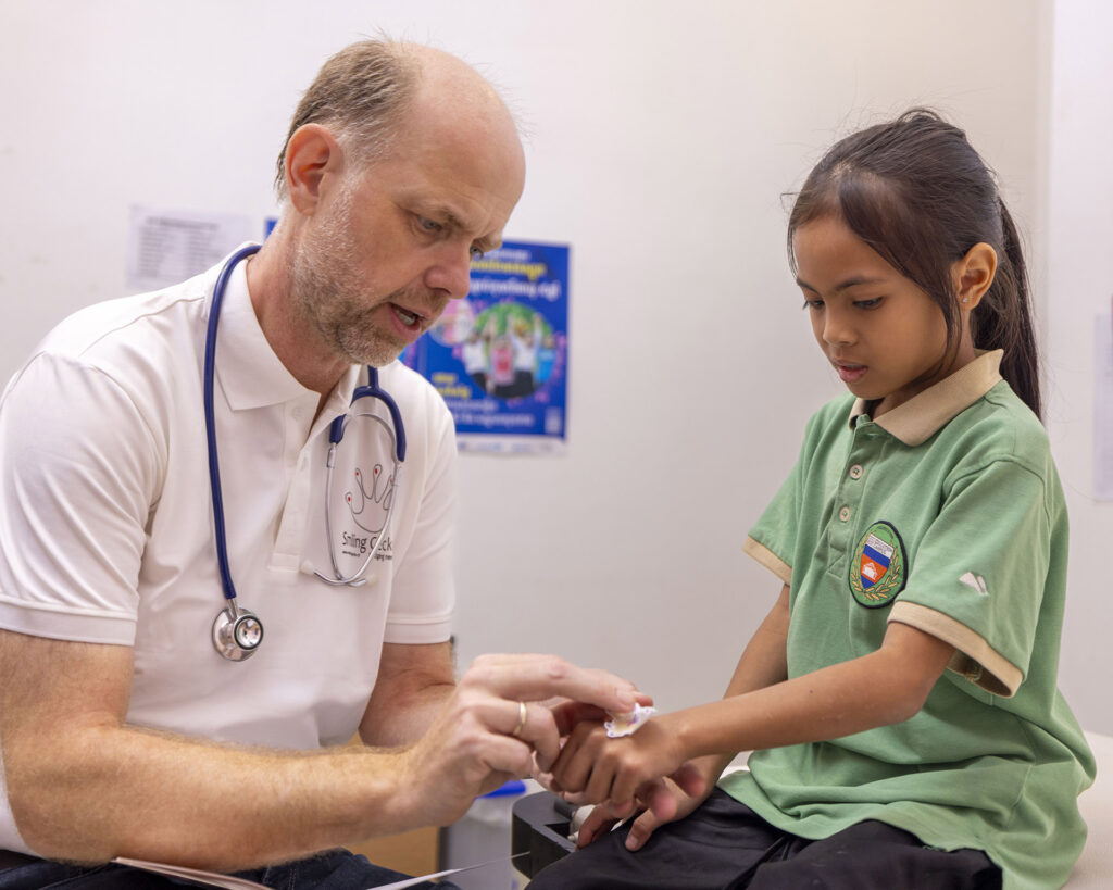 Un médecin examine la main d’une élève à la clinique.