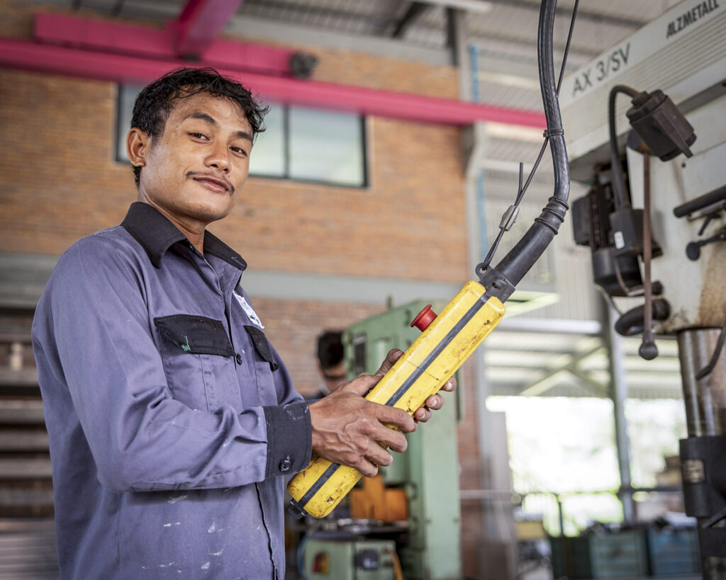 Staff member holding tools in the metal workshop.