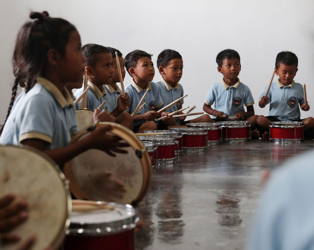 Kinder spielen gemeinsam Trommeln im Musikunterricht.
