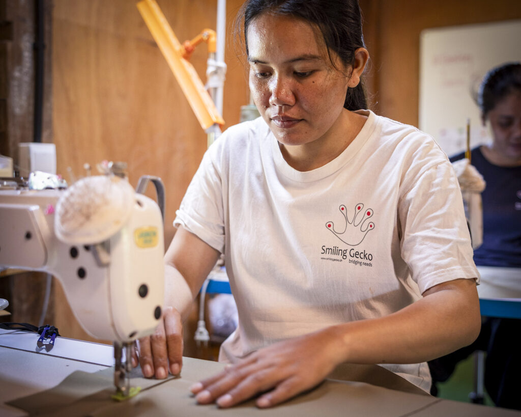 Staff member sewing at a sewing machine.