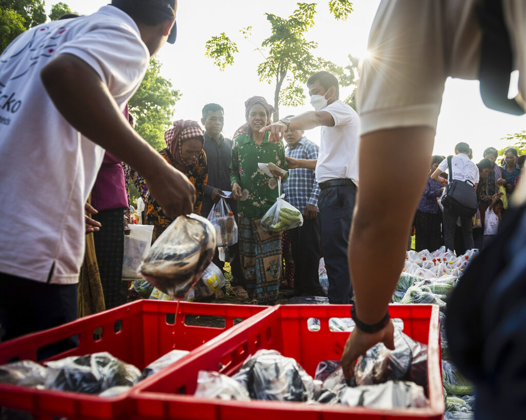 Des produits d’aide sont distribués depuis des caisses aux personnes qui attendent.