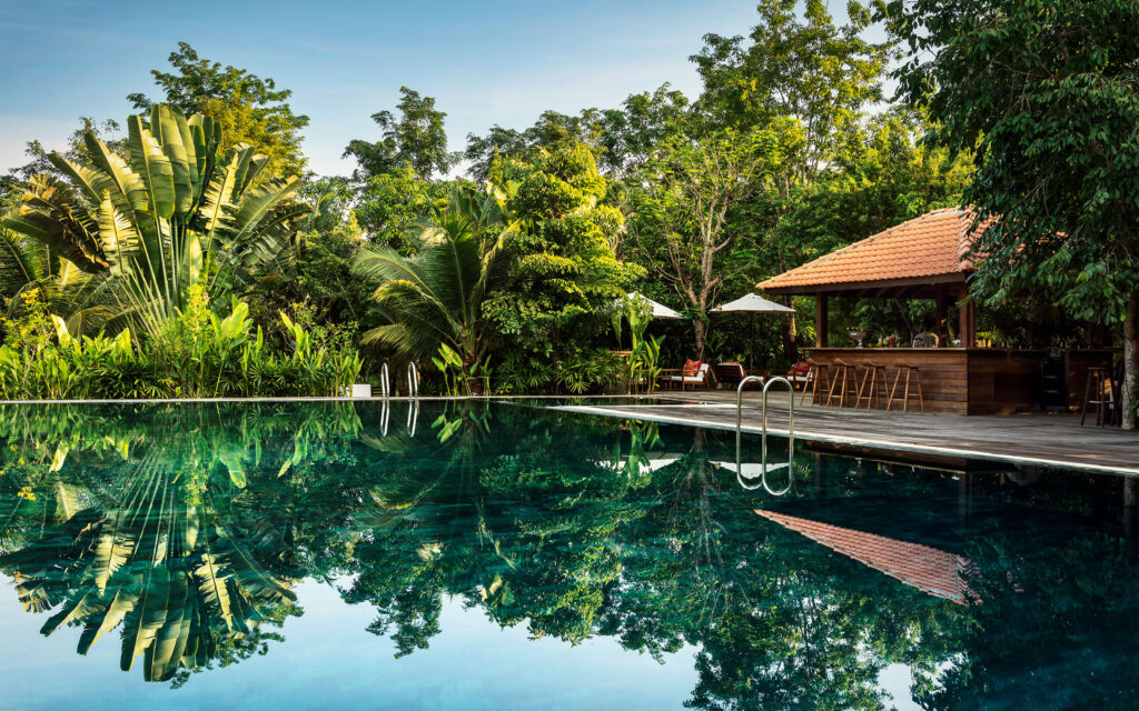 Pool und Poolbar zwischen tropischen Pflanzen im Farmhouse Resort.