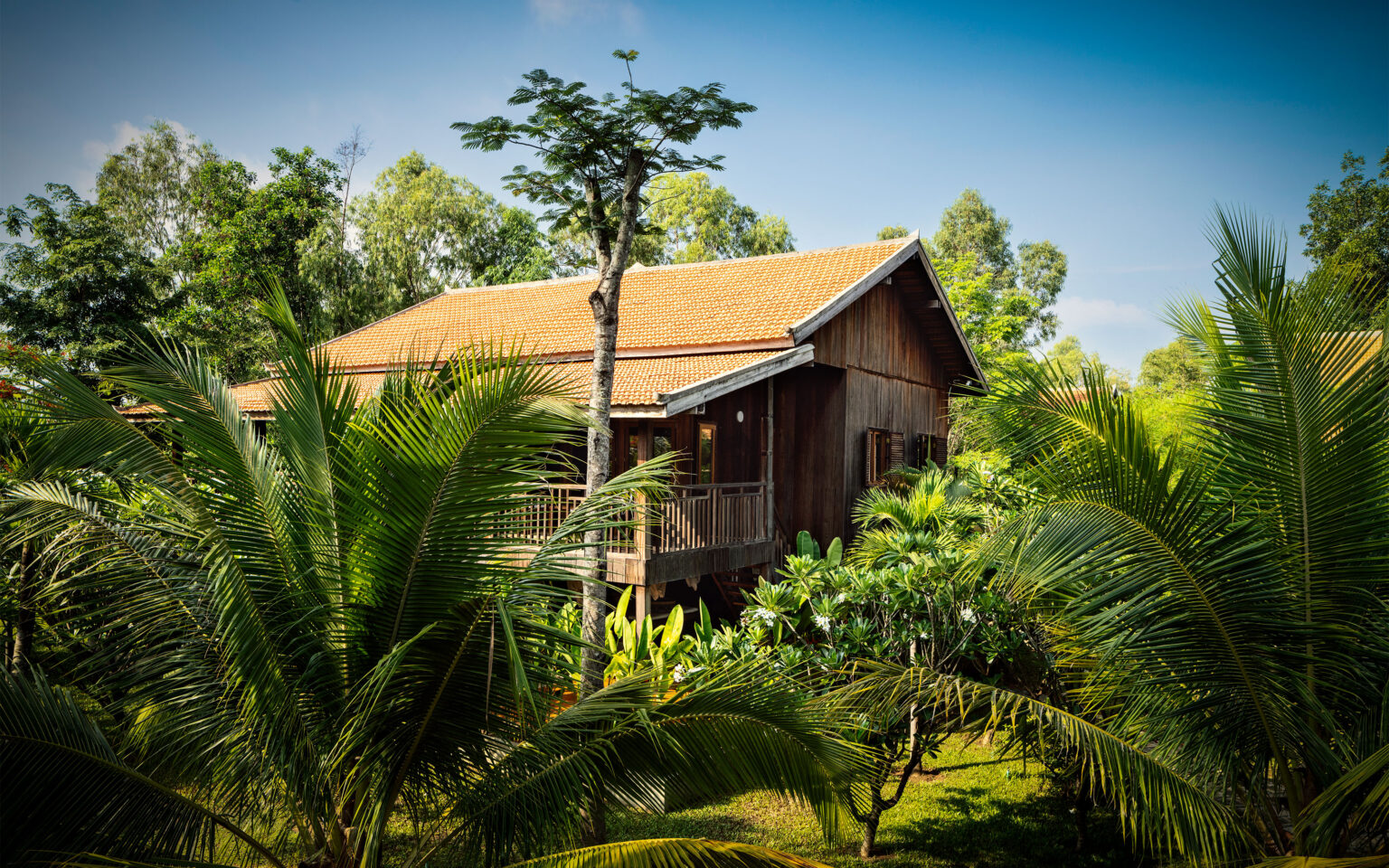 Holzbungalow im tropischen Garten des Farmhouse Resorts.