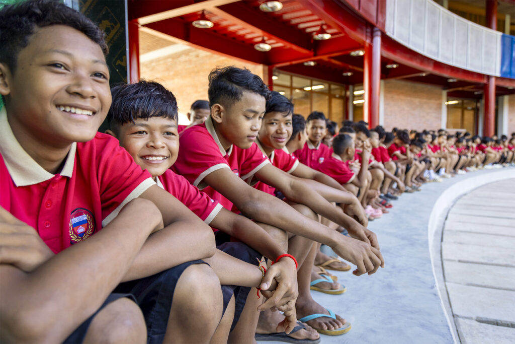 Schoolchildren sitting together outside the school building.