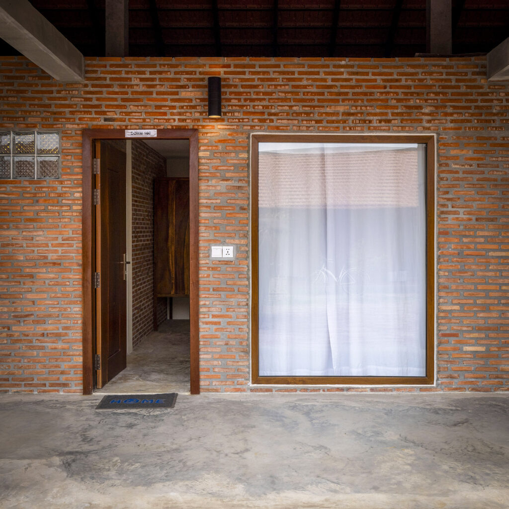 Entrance and window of a guest room in a brick building.