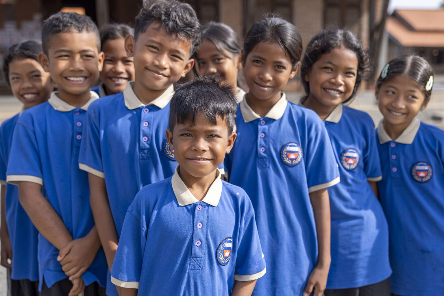 Group of schoolchildren wearing blue school shirts.