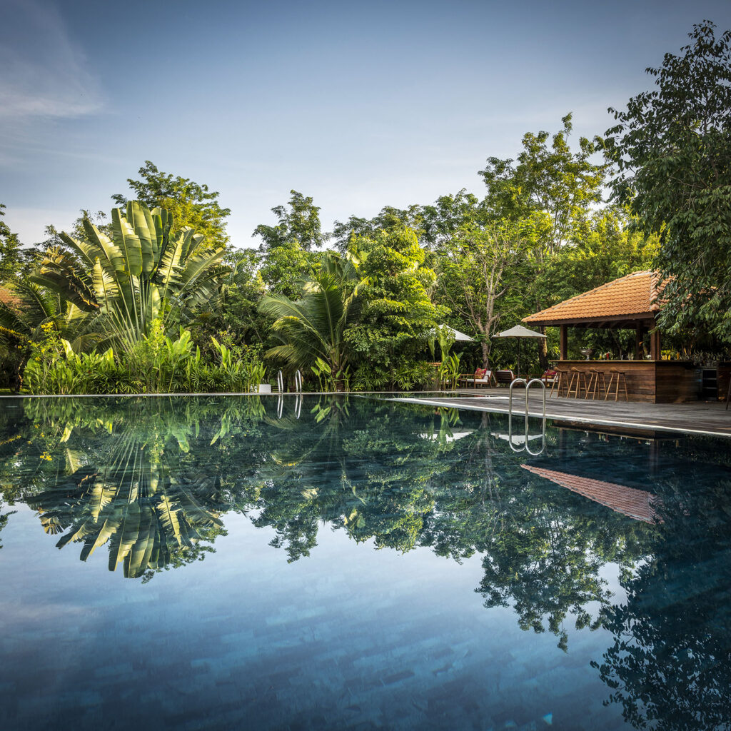 Pool and pool bar surrounded by tropical plants at Farmhouse Resort.